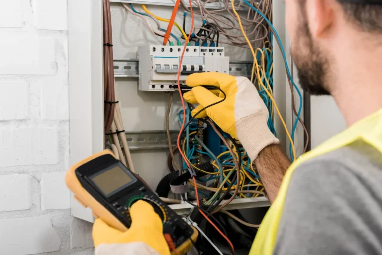 Electrician troubleshooting electrical panel with multimeter.